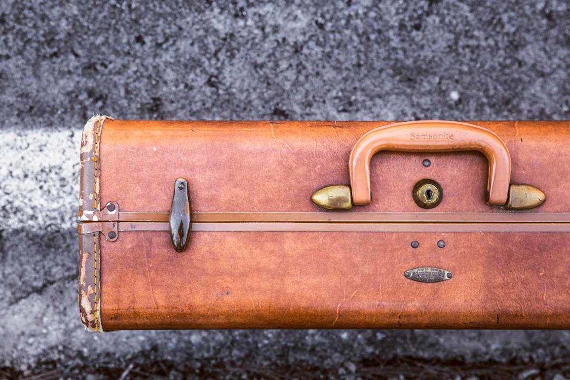 Vintage leather suitcase on textured surface.