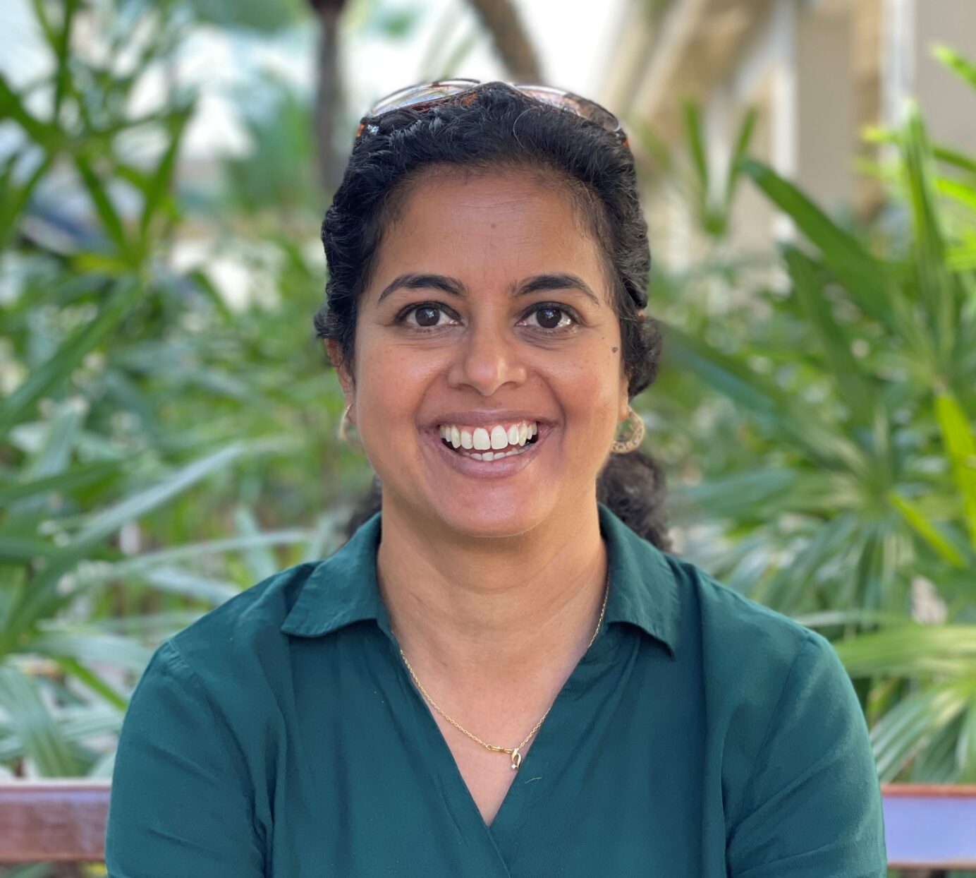 Mala Vivek smiling and looking at the camera and trees in the back