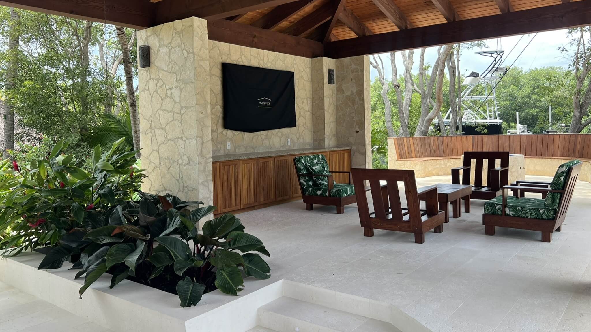 Outdoor patio with seating and tropical plants.