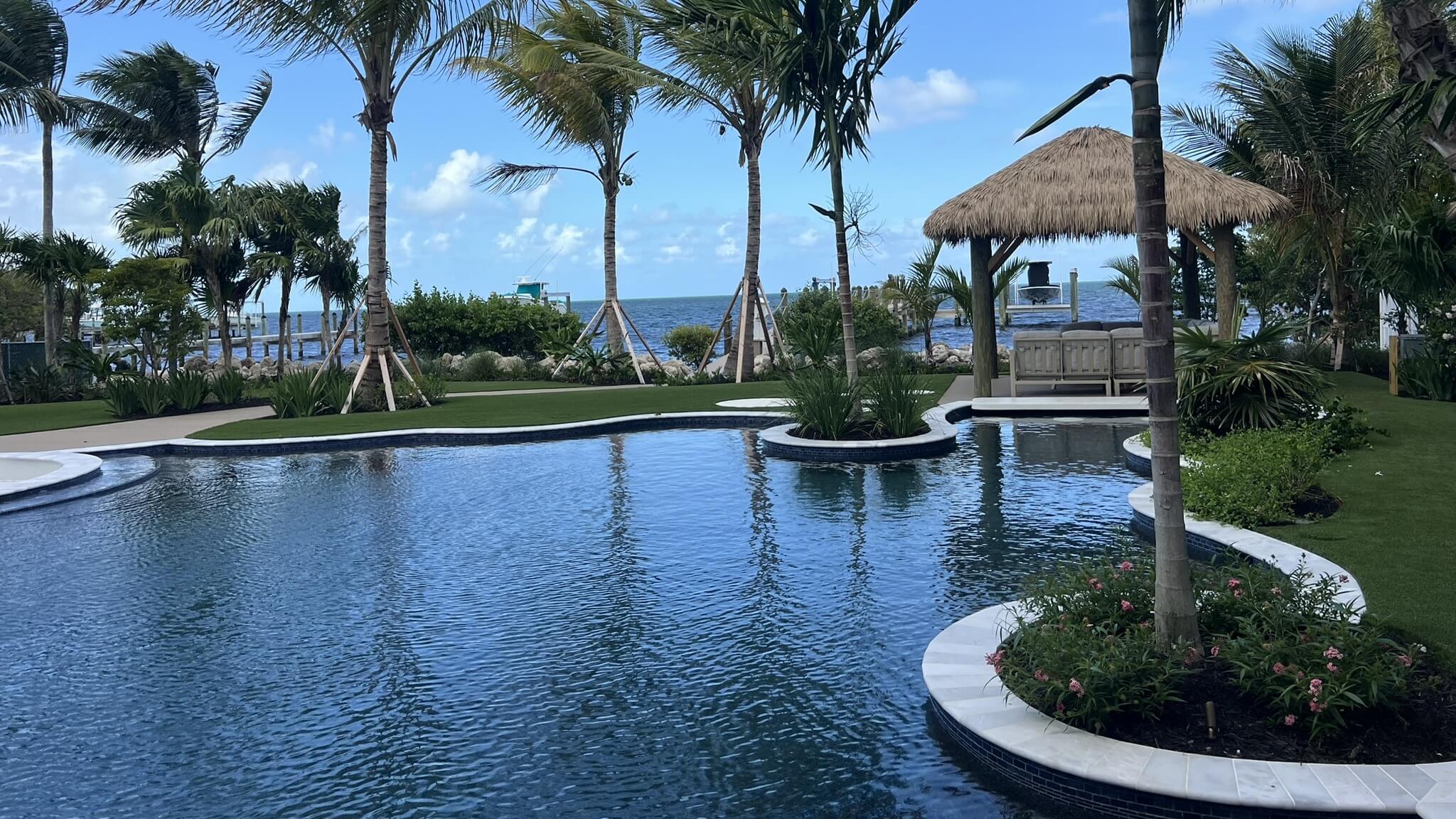 Tropical poolside with palm trees and gazebo.