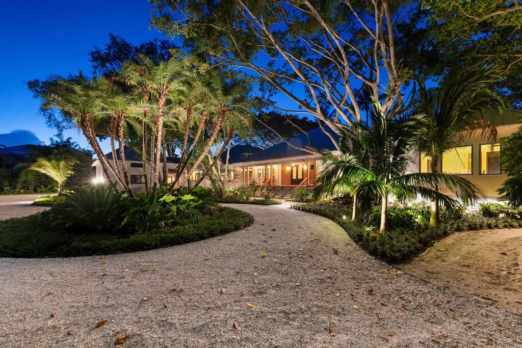 Tropical house exterior with illuminated pathway.