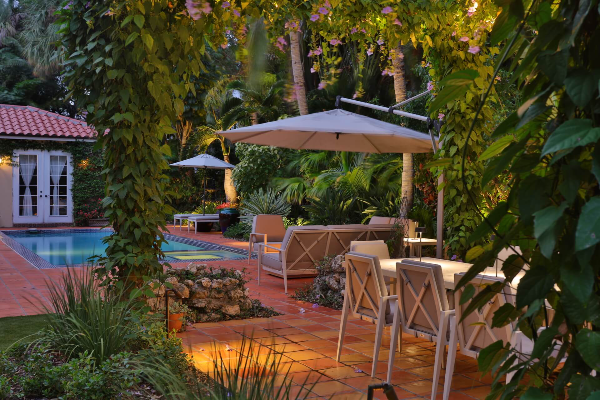 Lush garden patio with pool and furniture.