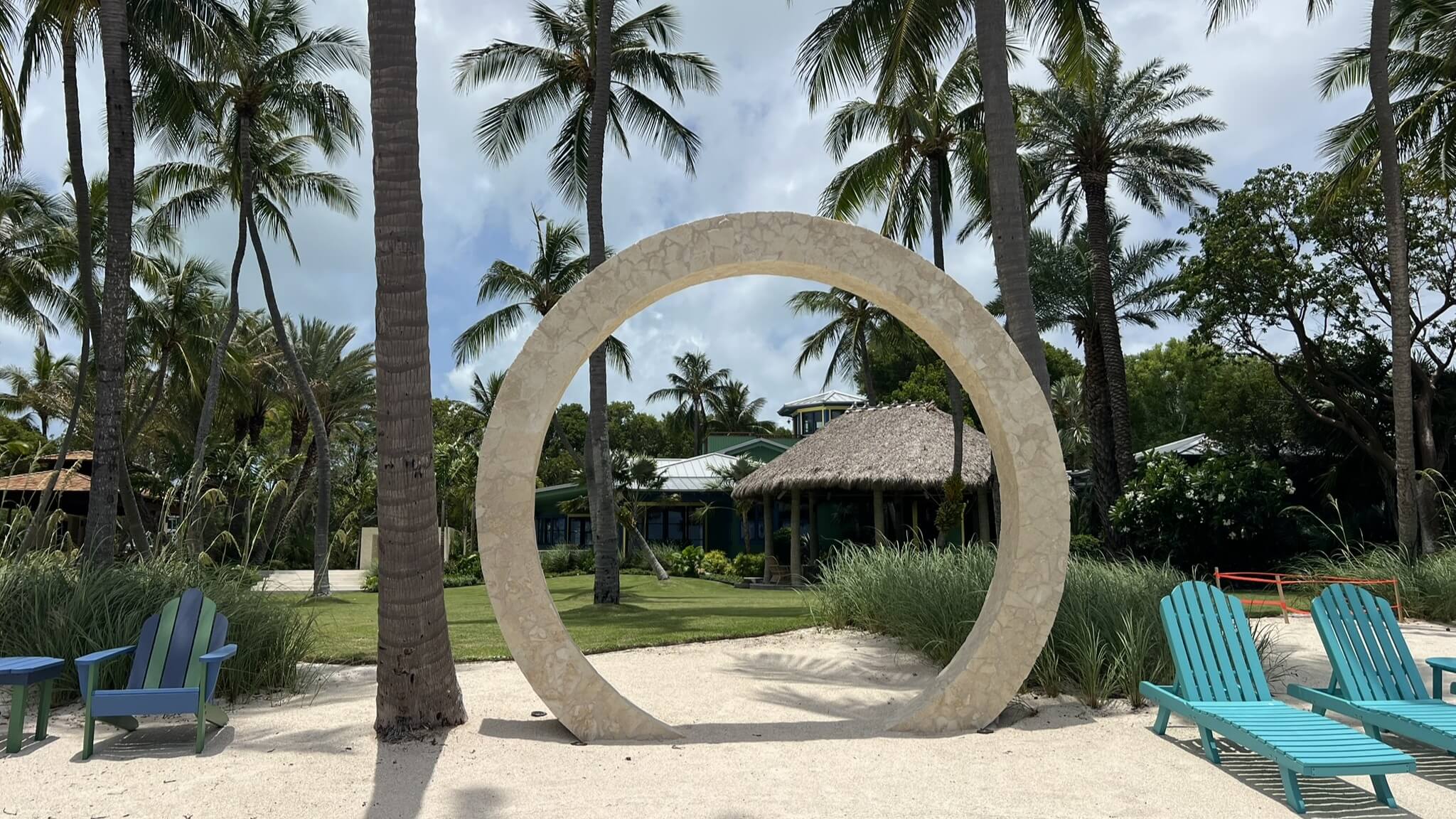 Stone circle with palm trees and chairs.