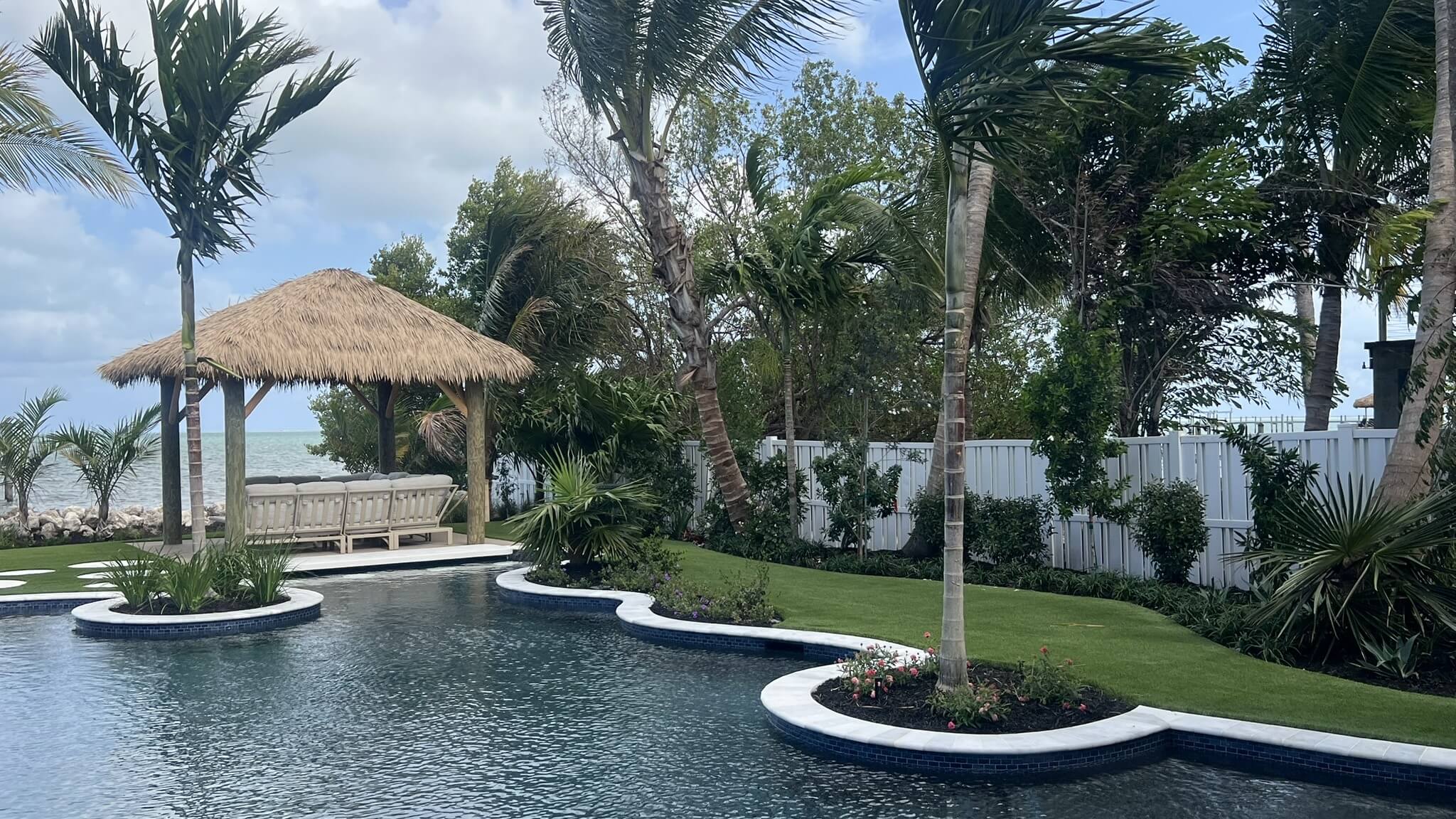 Tropical poolside with a thatched gazebo.