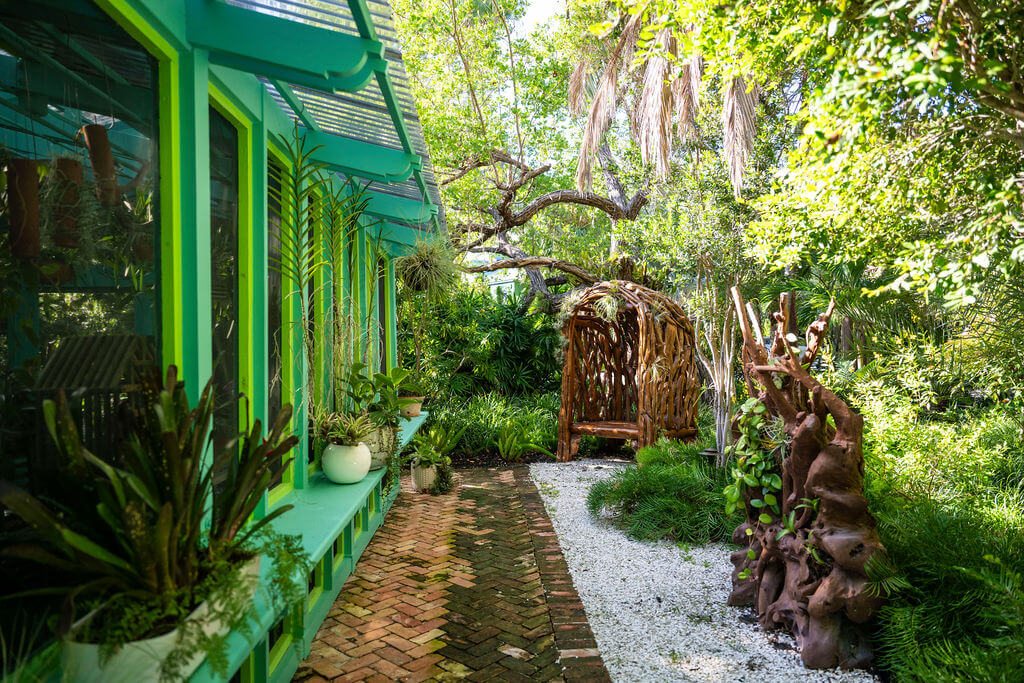 Garden path beside vibrant green house exterior.