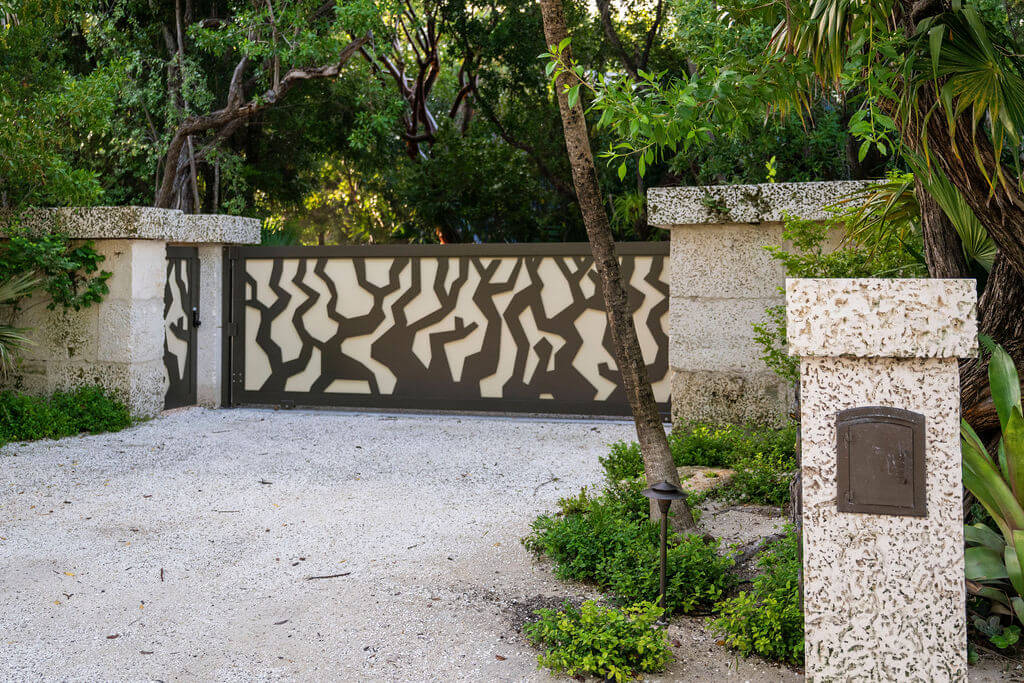 Decorative gate with abstract pattern and trees.