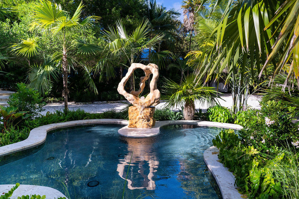 Tropical garden with a central stone sculpture.