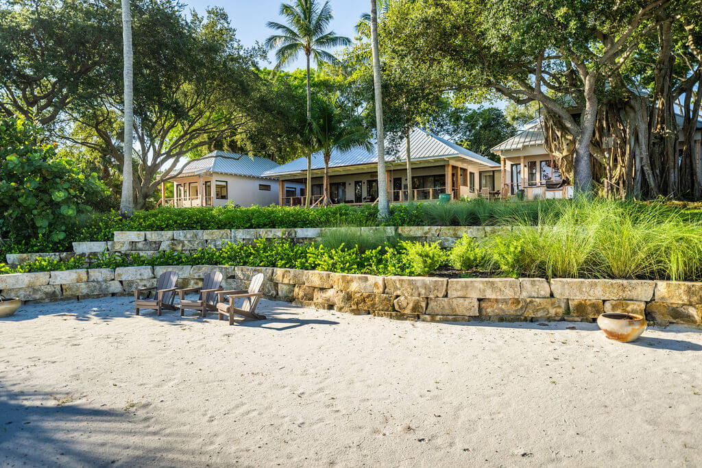 Beachfront house with trees and sandy area.