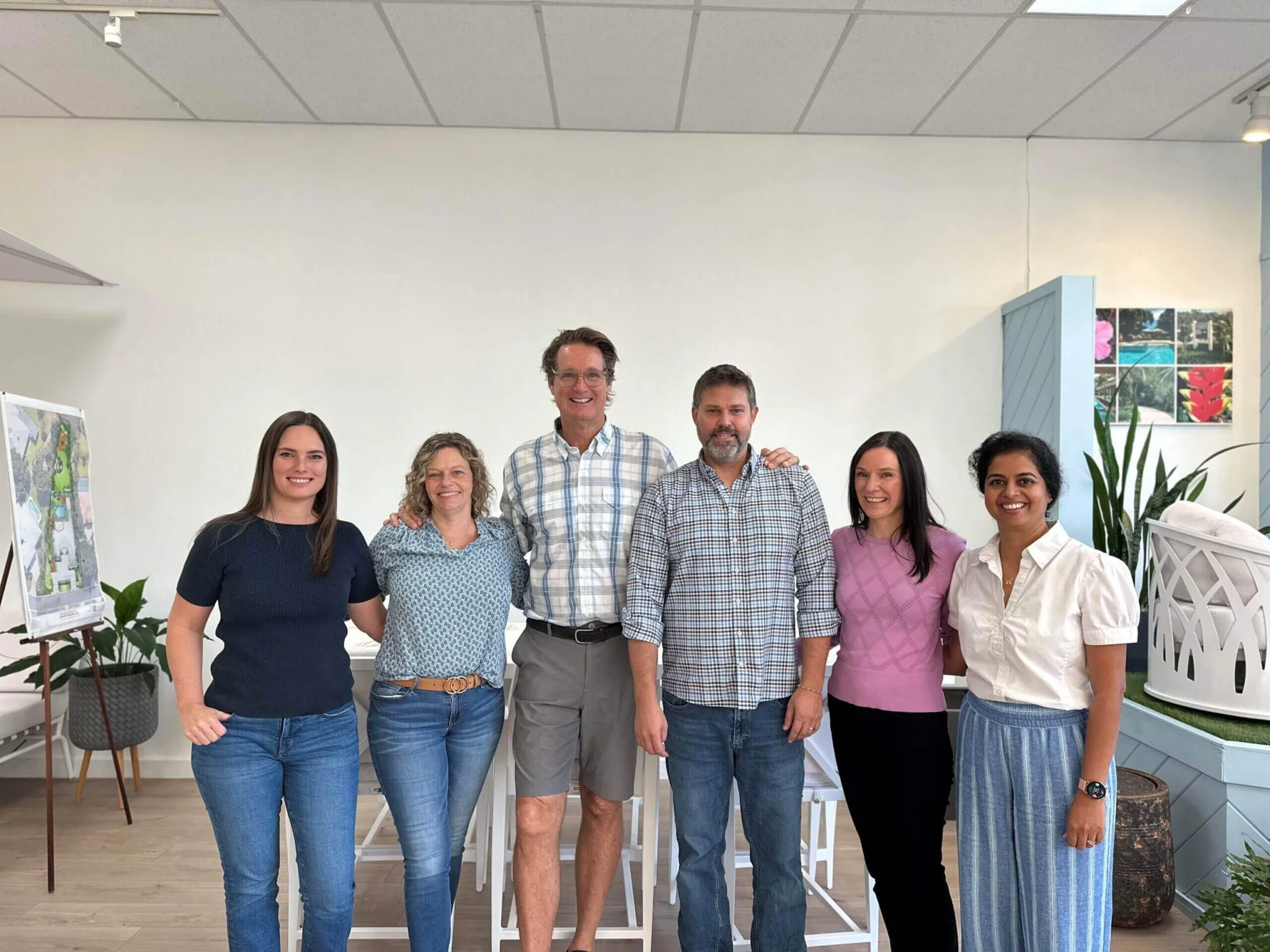 Group of six people standing together indoors.